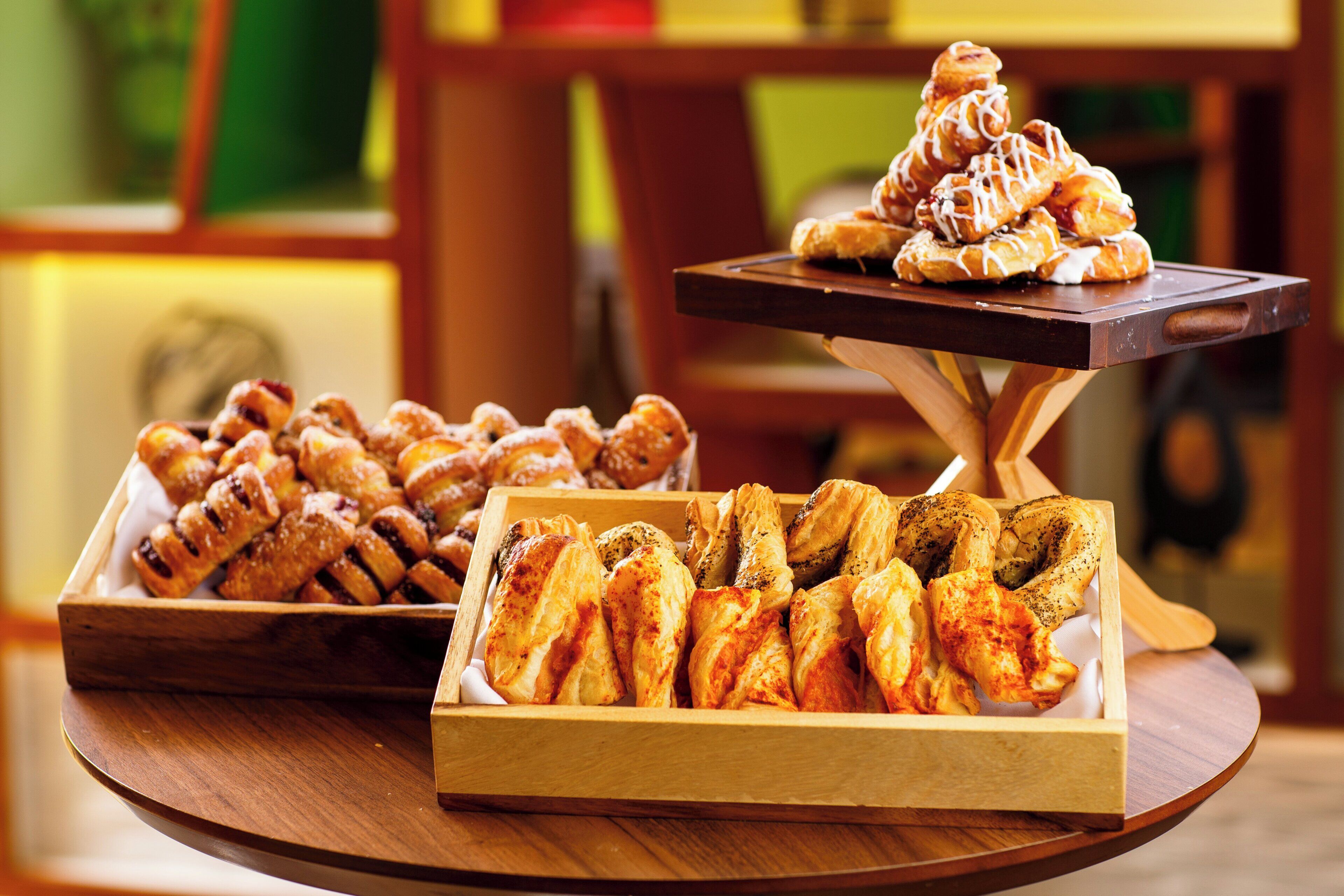 A wooden table with three trays of pastries.
