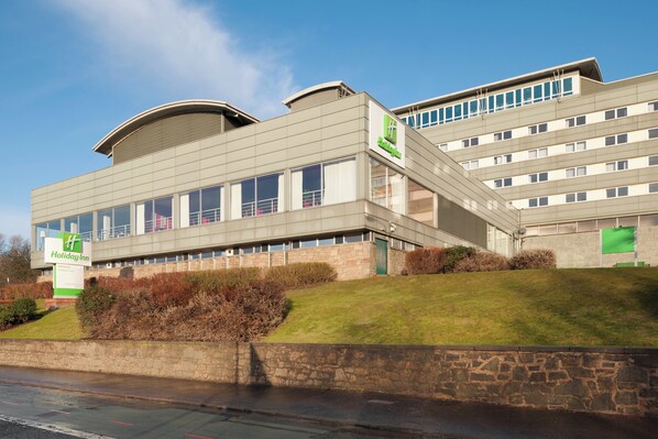 A modern Holiday Inn hotel with a two-story structure, a prominent entrance, and a landscaped front yard.