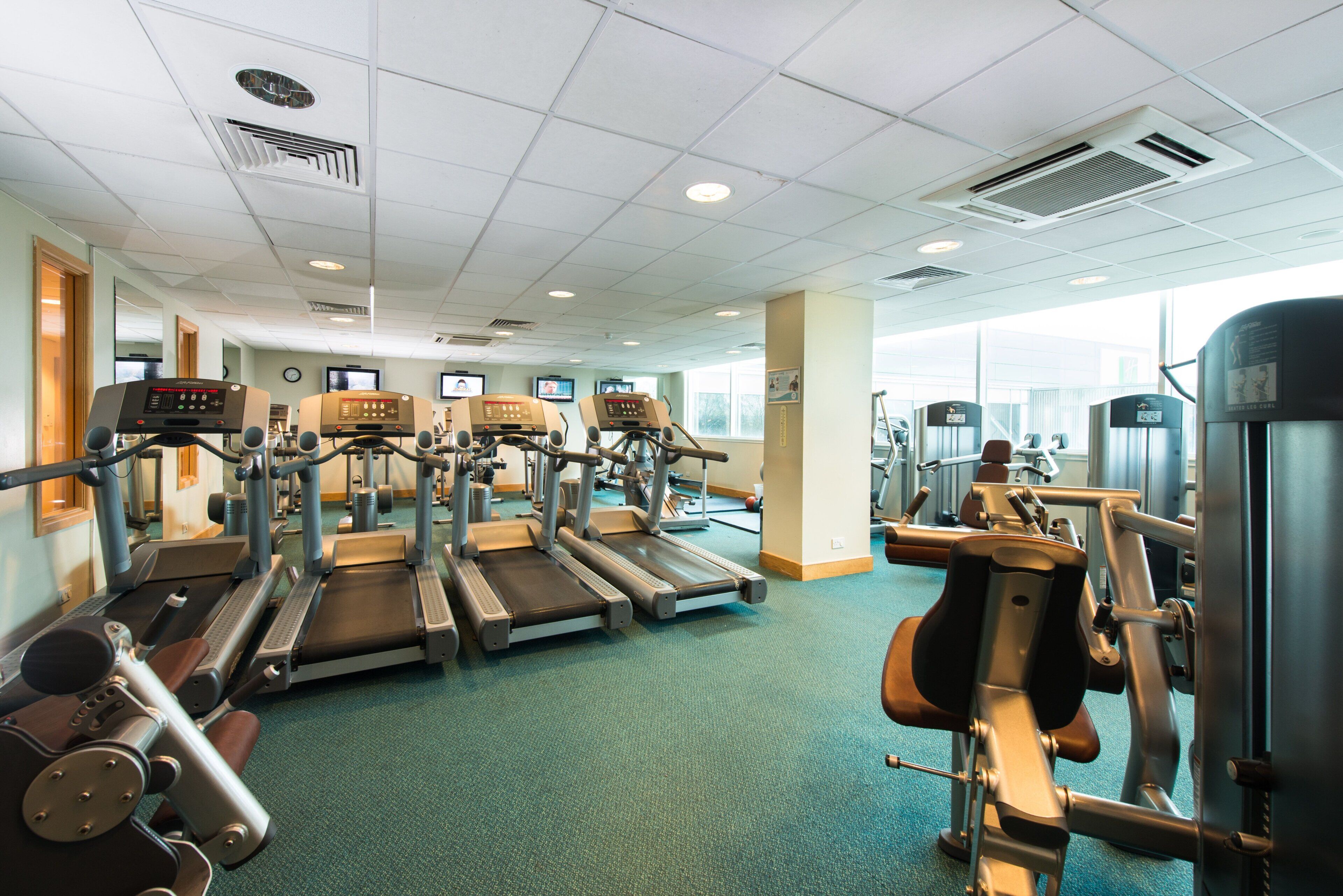 Ein Fitnessstudio mit Laufbändern, Kraftgeräten und Trainingsausrüstung.