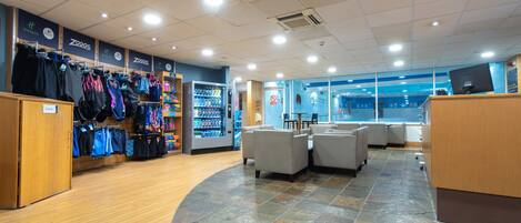 A clothing store with racks of clothes, a vending machine, and seating areas.