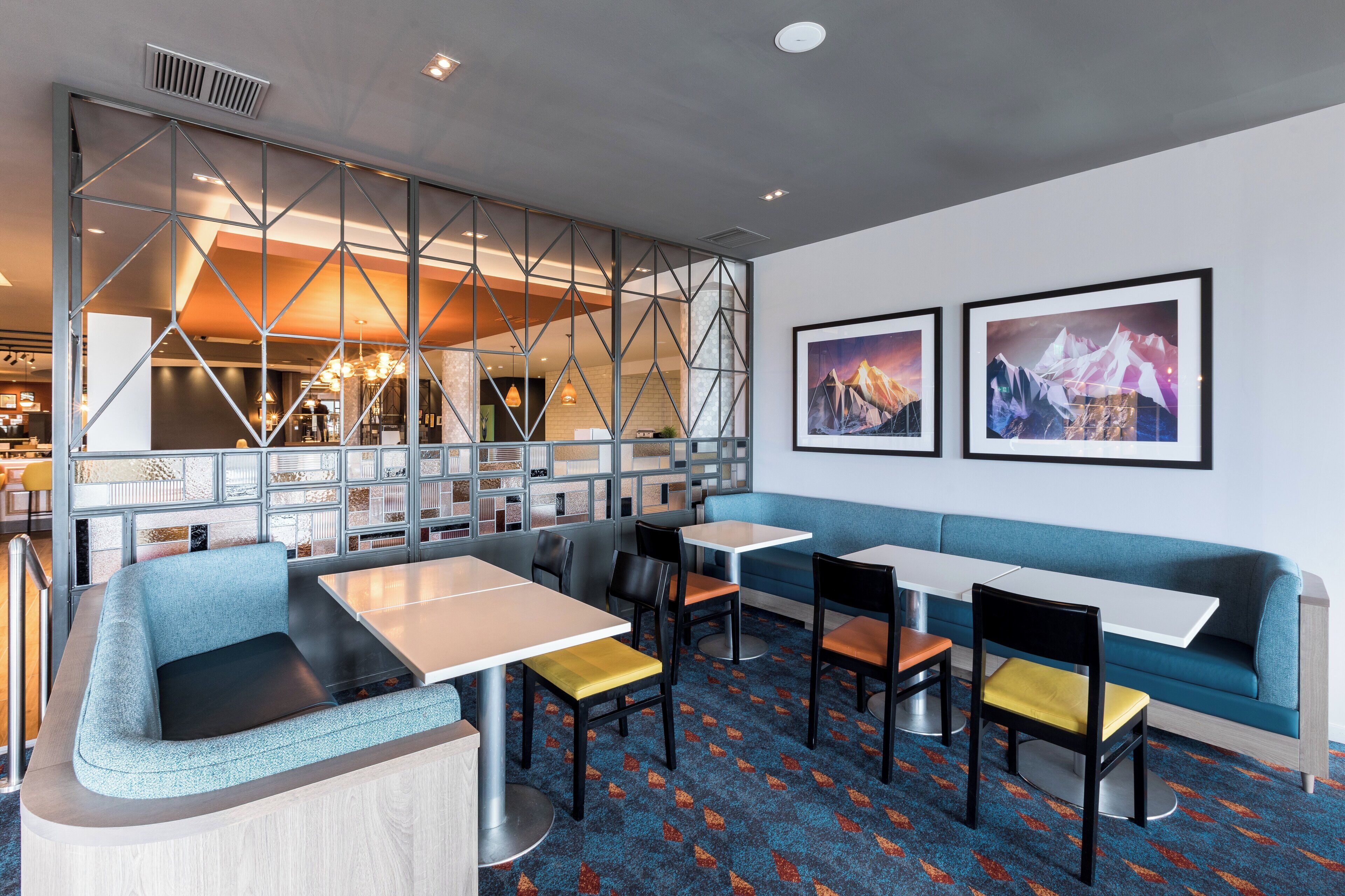 A modern restaurant with booths, tables, and a patterned carpet.