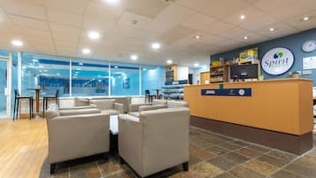 Un espace d’accueil avec un bureau en bois, des canapés beiges et un mur bleu orné d’une enseigne indiquant « Spirit Health Club ».