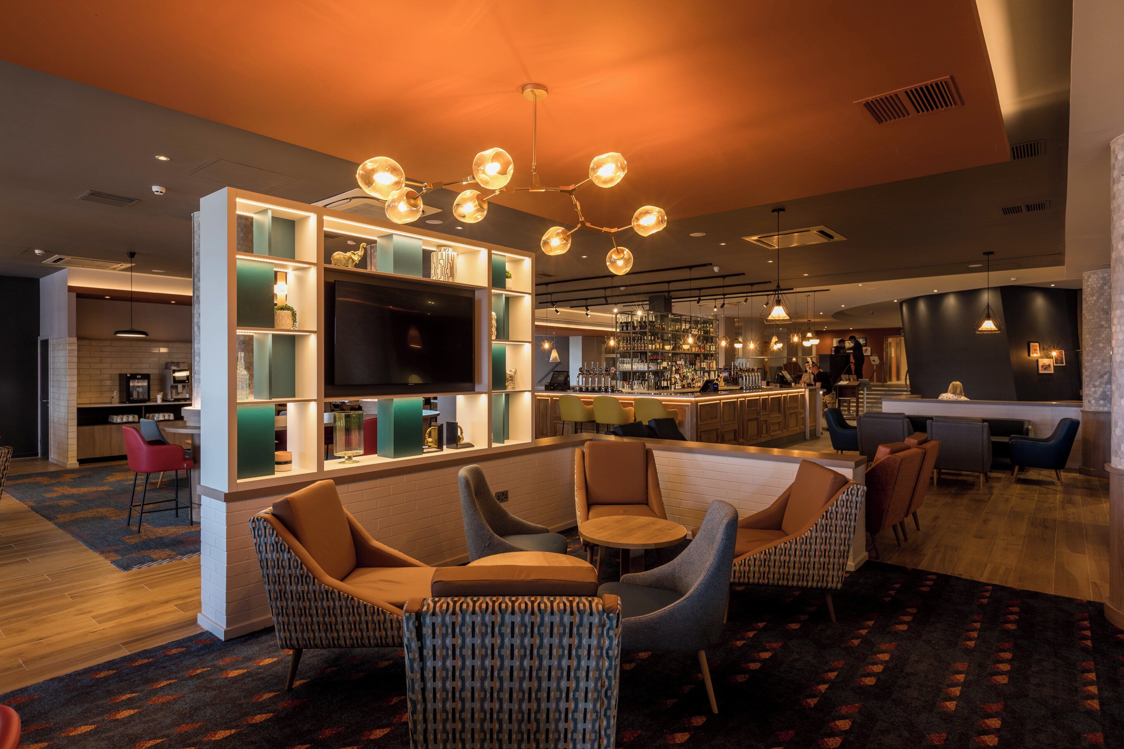 Un área de bar moderna con asientos y una televisión.