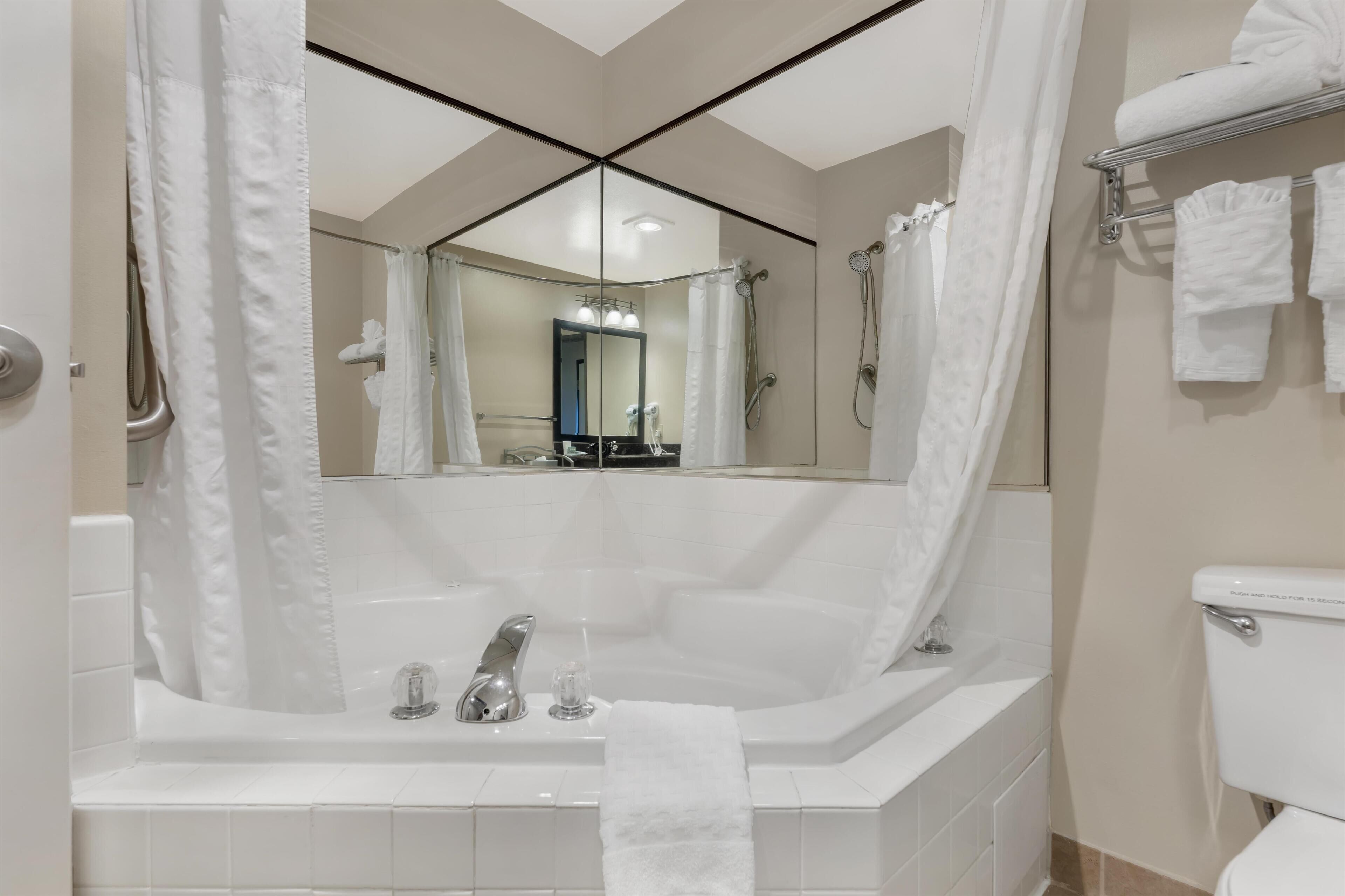 A modern bathroom with a large bathtub, a toilet, and a shower area.