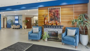 A lobby with two blue armchairs, a fireplace, and a large painting on the wall. - Best Western Sky Valley Inn (Monroe)