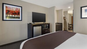 A hotel room with a bed, a flat-screen TV, a kitchenette, and a painting on the wall. - Best Western Sky Valley Inn (Monroe)