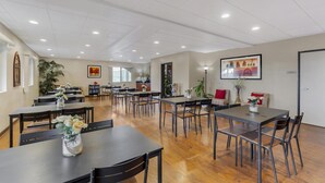 A spacious dining area with multiple tables and chairs, a kitchen in the background, and a framed artwork on the wall. - Best Western Sky Valley Inn (Monroe)