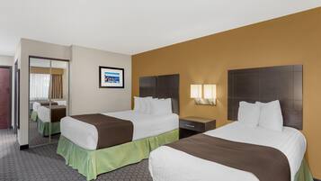 A hotel room with two beds, a mirror, a framed picture on the wall, and a nightstand with lamps.