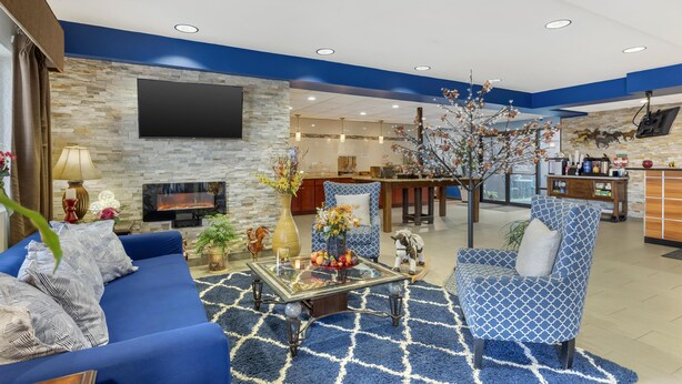 A modern living room with a blue sofa, a glass coffee table, and a fireplace. - Best Western Sky Valley Inn (Monroe)