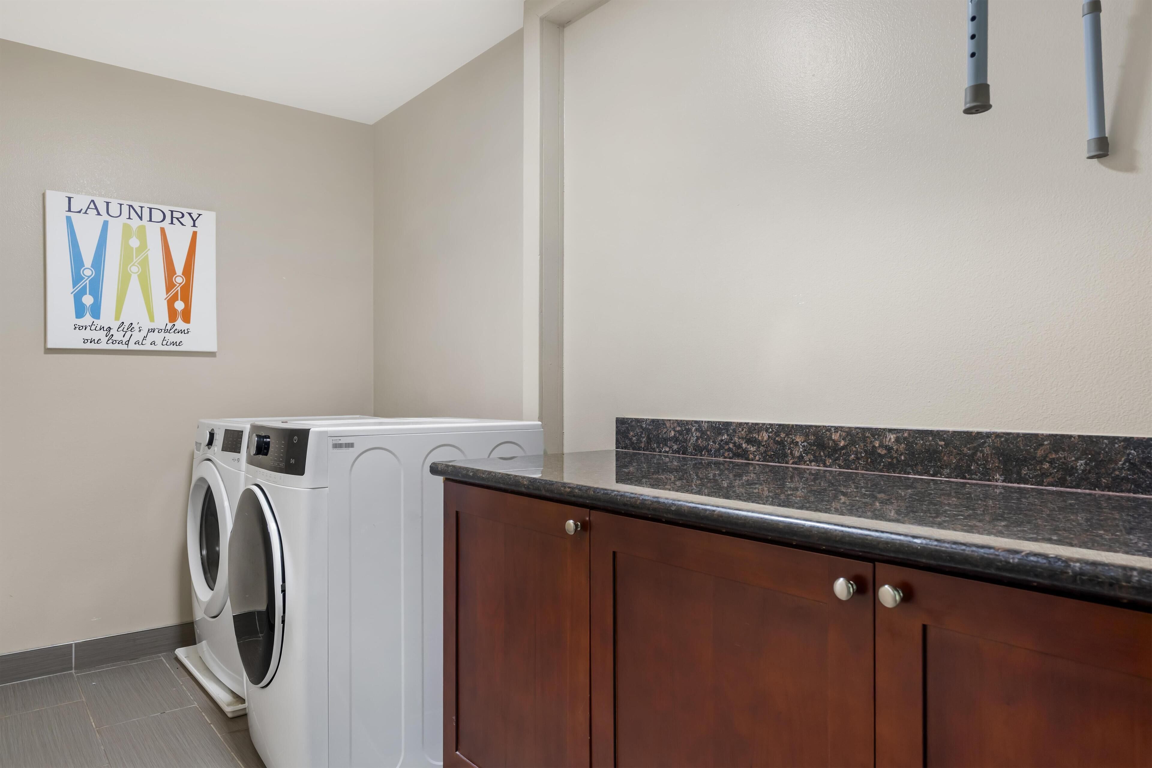 A laundry room with a washing machine, a drying machine, and a wooden cabinet.