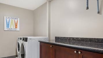 A laundry room with a washing machine, a drying machine, and a wooden cabinet.