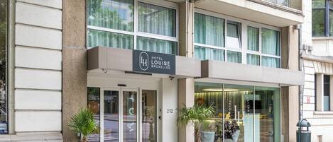 A hotel entrance with a sign reading "Hotel Louise Bruxelles".