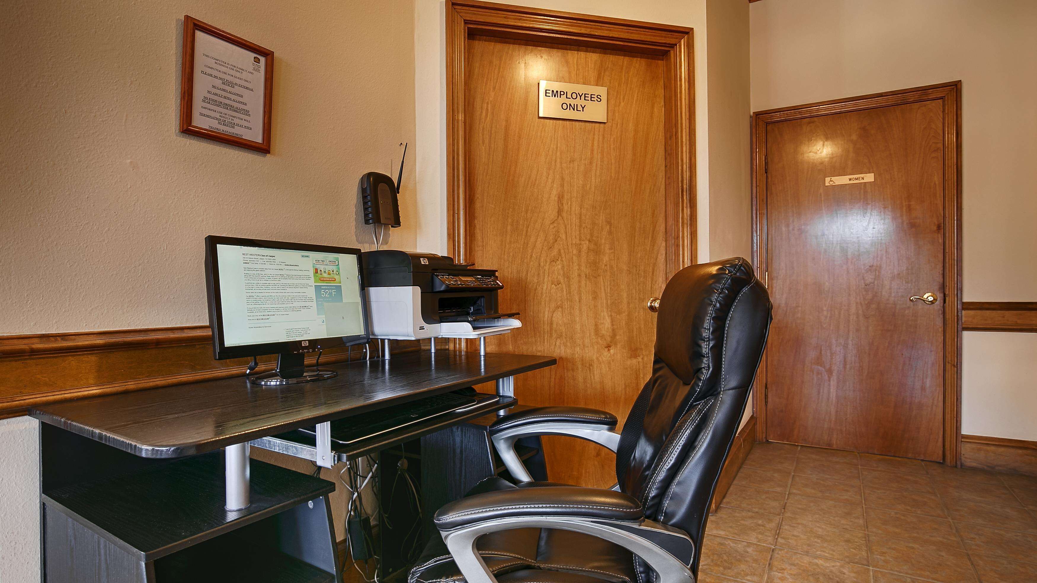 Un mostrador de recepción con una computadora, una impresora y una silla de cuero. Hay un letrero en la puerta que dice 'Sólo personal'.