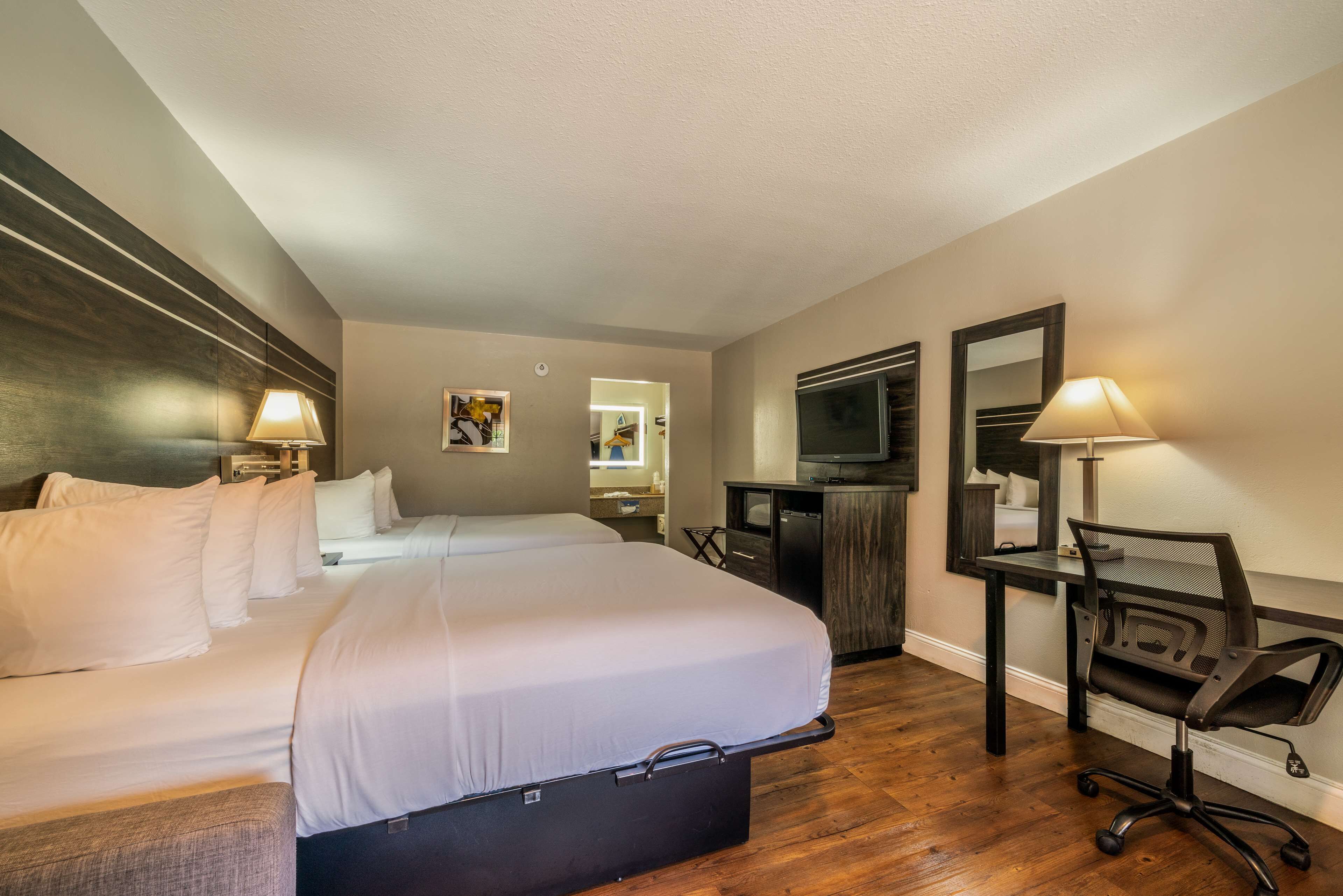 Een hotelkamer met een groot bed, een bureau met een computer, een televisie en een stoel.