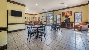 A spacious dining area with multiple tables and chairs, a television mounted on the wall, and a kitchen area with a bar. - Best Western Inn Of Jasper (Jasper)
