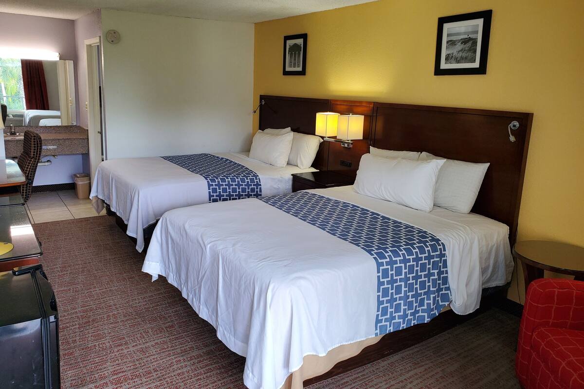 Ett hotellrum med två sängar, ett skrivbord, en stol och ett litet bord.
