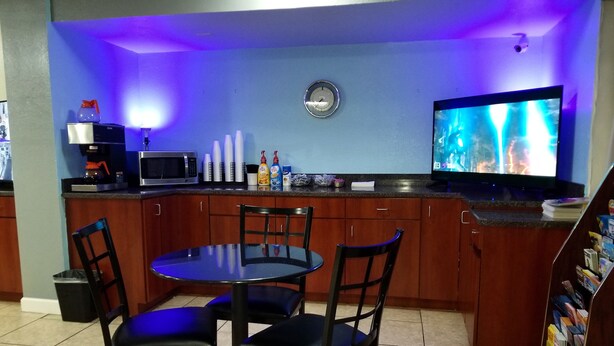 A kitchen with a dining table, chairs, a microwave, and a television. - Econo Inn (Ormond Beach)