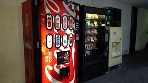 A Coca-Cola branded vending machine with a selection of drinks and snacks, and an adjacent ice dispenser. - Econo Inn (Ormond Beach)