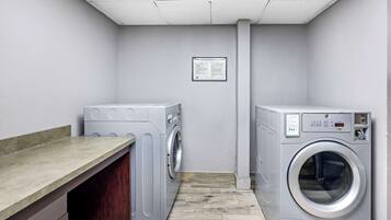 Un cuarto de lavandería con dos lavadoras, un banco de madera y un aviso en la pared.