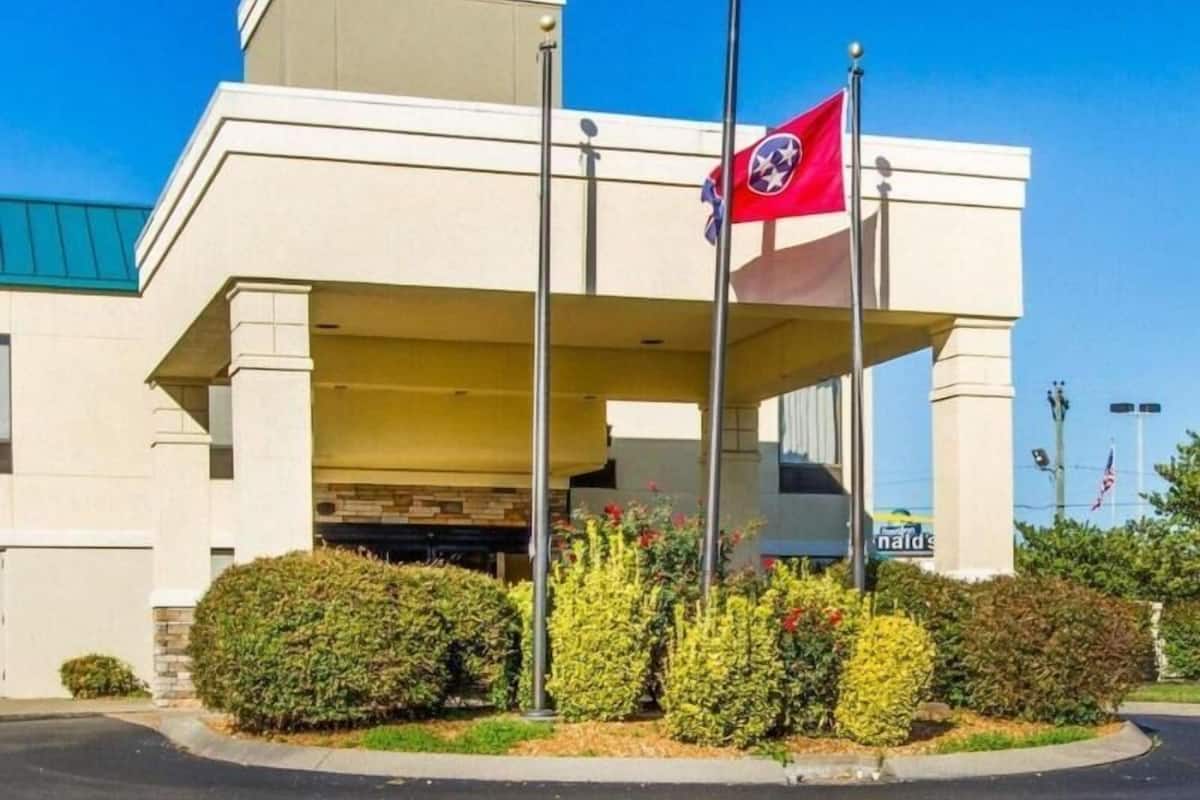 Ein Gebäude mit flachem Dach, einer Fahnenmast mit einer Flagge und einer begrünten Fläche mit Büschen.