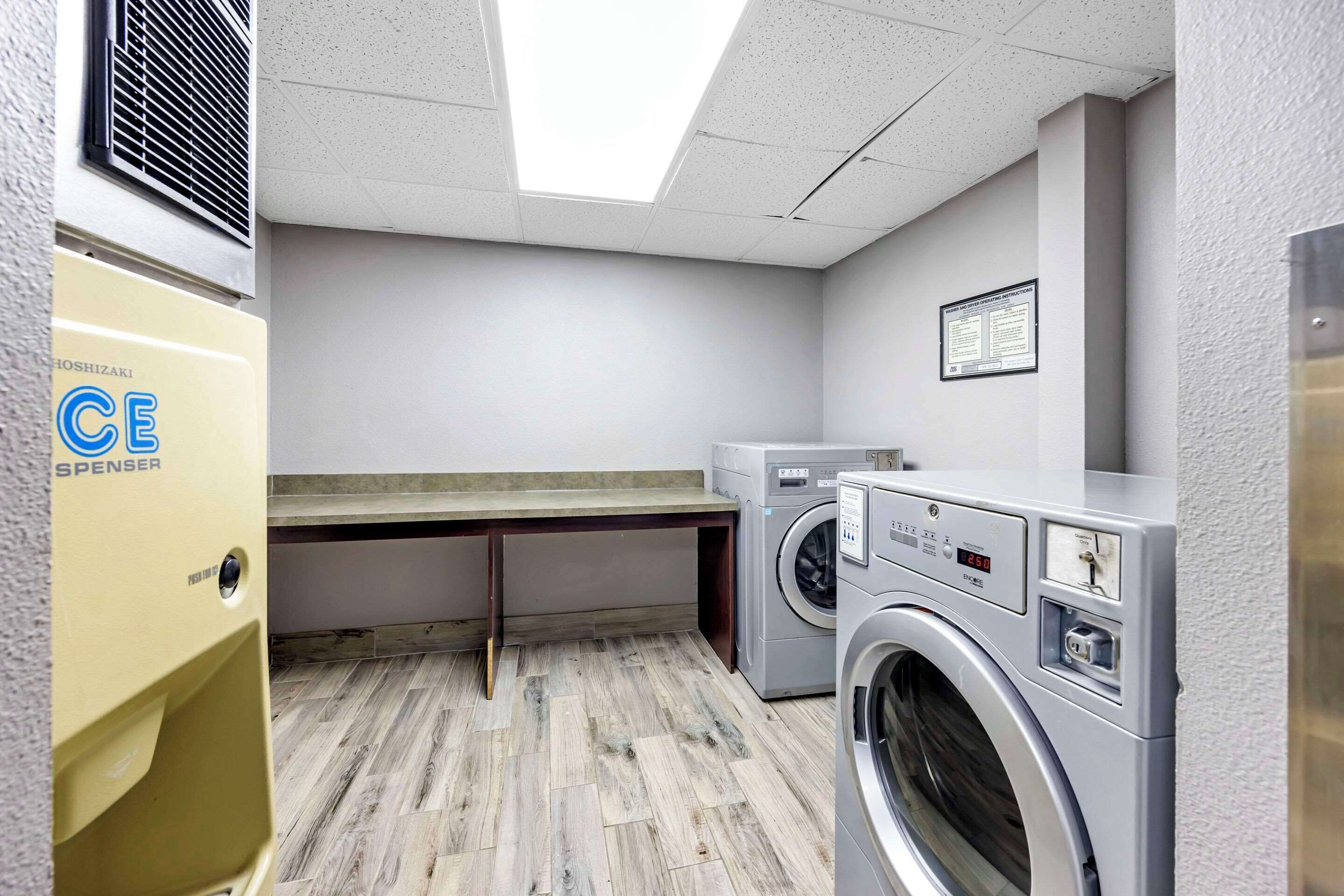 A laundry room with a washing machine, dryer, and a yellow CE Spenser appliance.