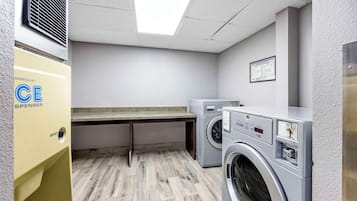 A laundry room with a washing machine, dryer, and a yellow CE Spenser appliance.