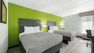Een hotelkamer met twee bedden, een bureau en een stoel.