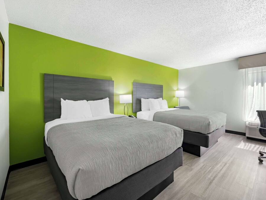 Een hotelkamer met twee bedden, een bureau en een stoel.
