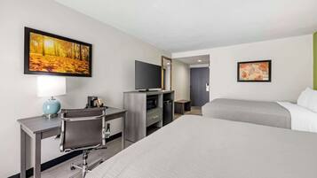 A hotel room with a large bed, a desk with a chair, a television, and a microwave.