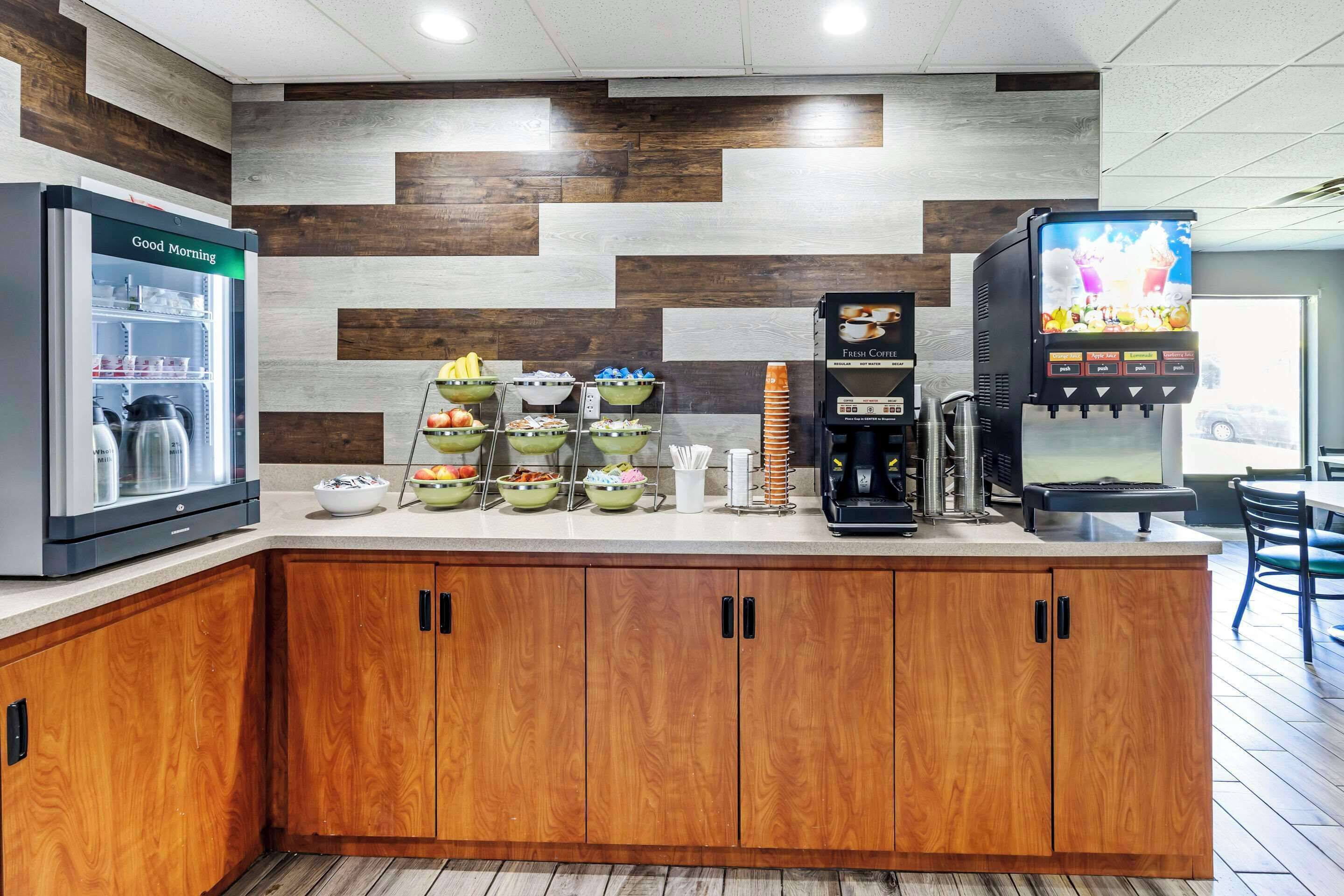 A breakfast bar with a refrigerator, coffee machine, and a TV displaying a food menu.