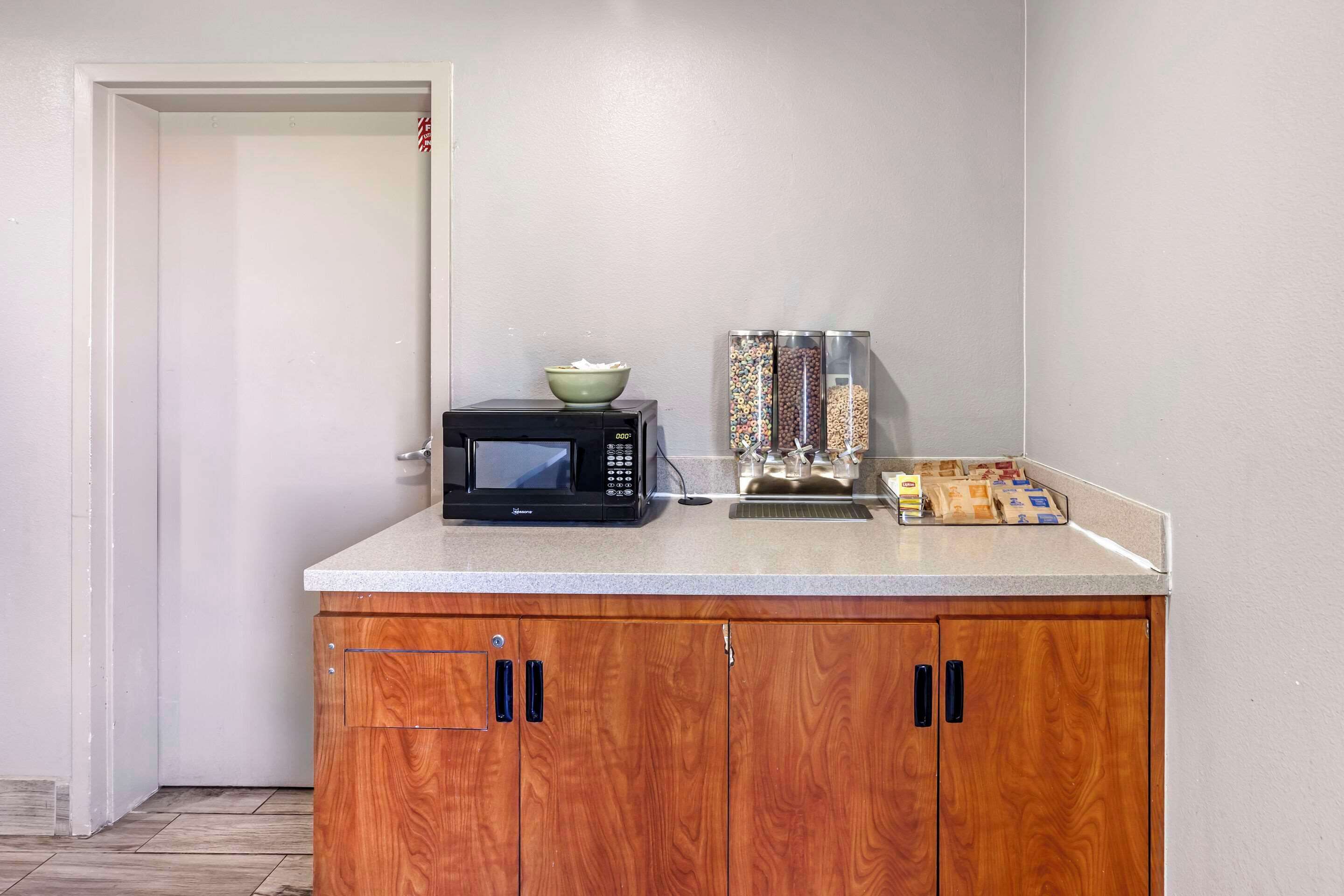 A kitchenette with a microwave, a bowl, and a coffee machine.