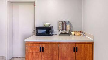 A kitchenette with a microwave, a bowl, and a coffee machine.