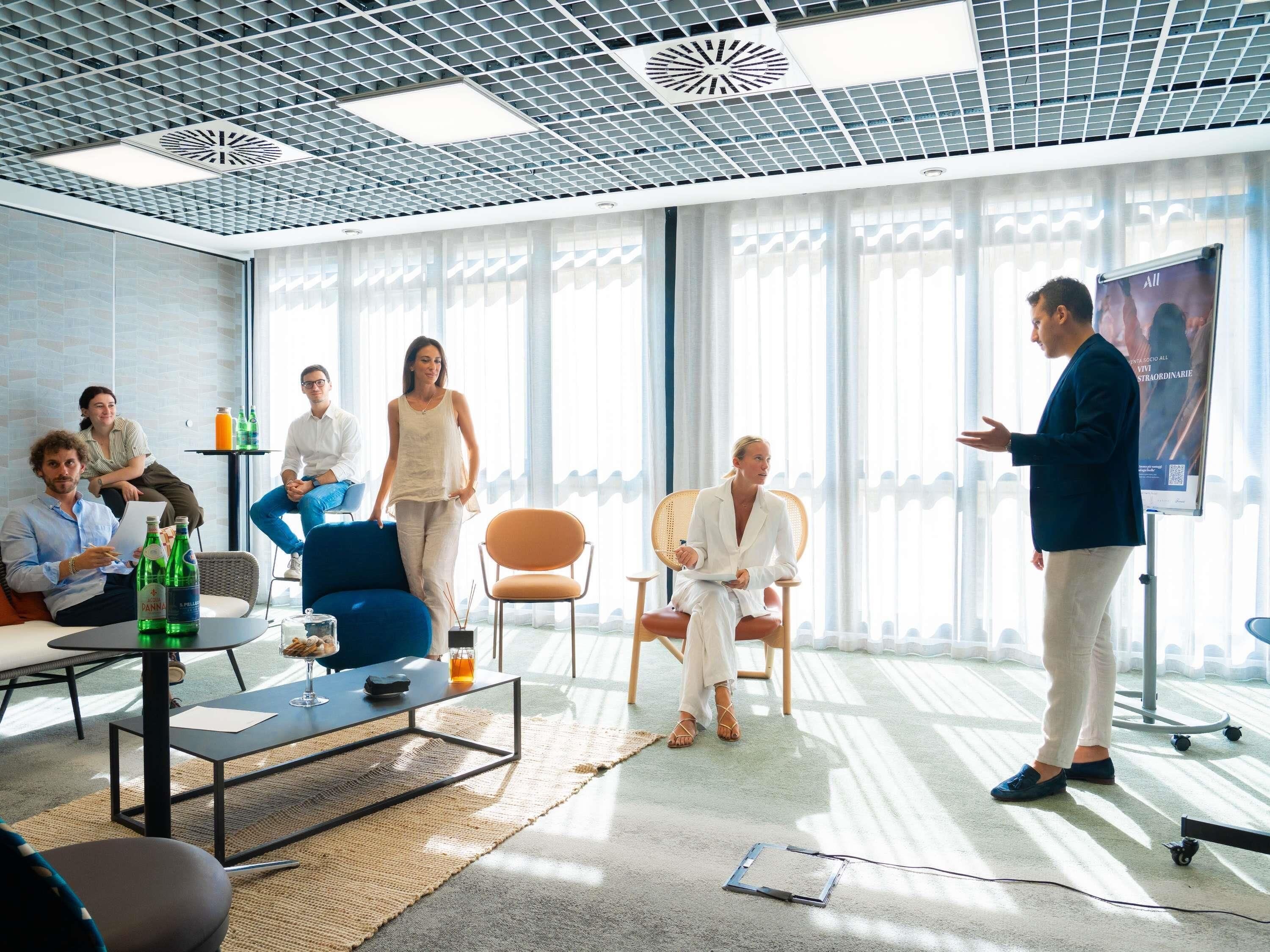 A modern meeting room with a glass partition, a projector screen, and a presentation stand.