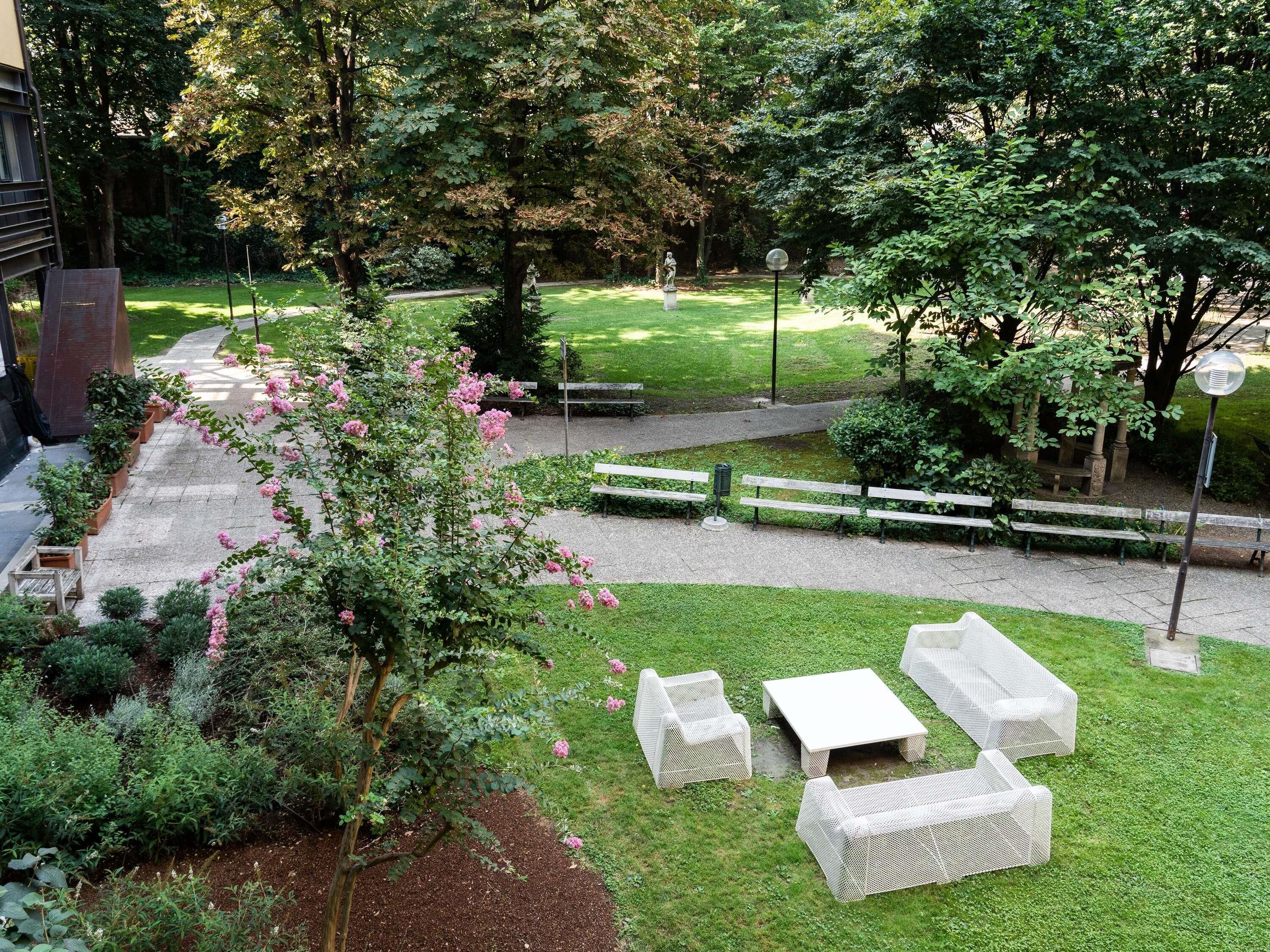 A garden patio with outdoor furniture, a pathway, and a grassy area with trees.