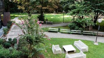 A garden patio with outdoor furniture, a pathway, and a grassy area with trees.