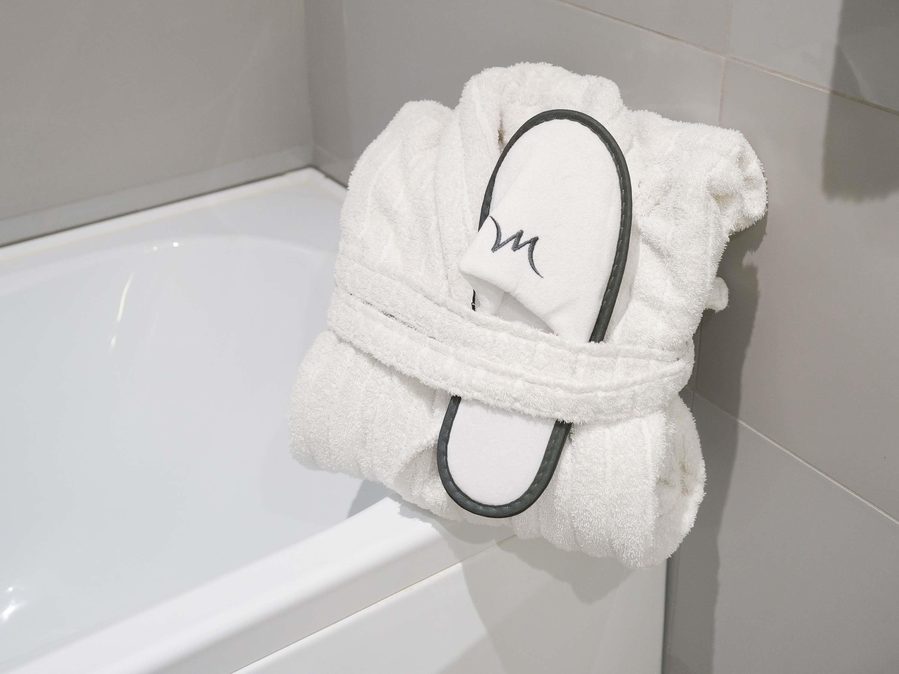 A white bathtub with a towel wrapped around a slipper.