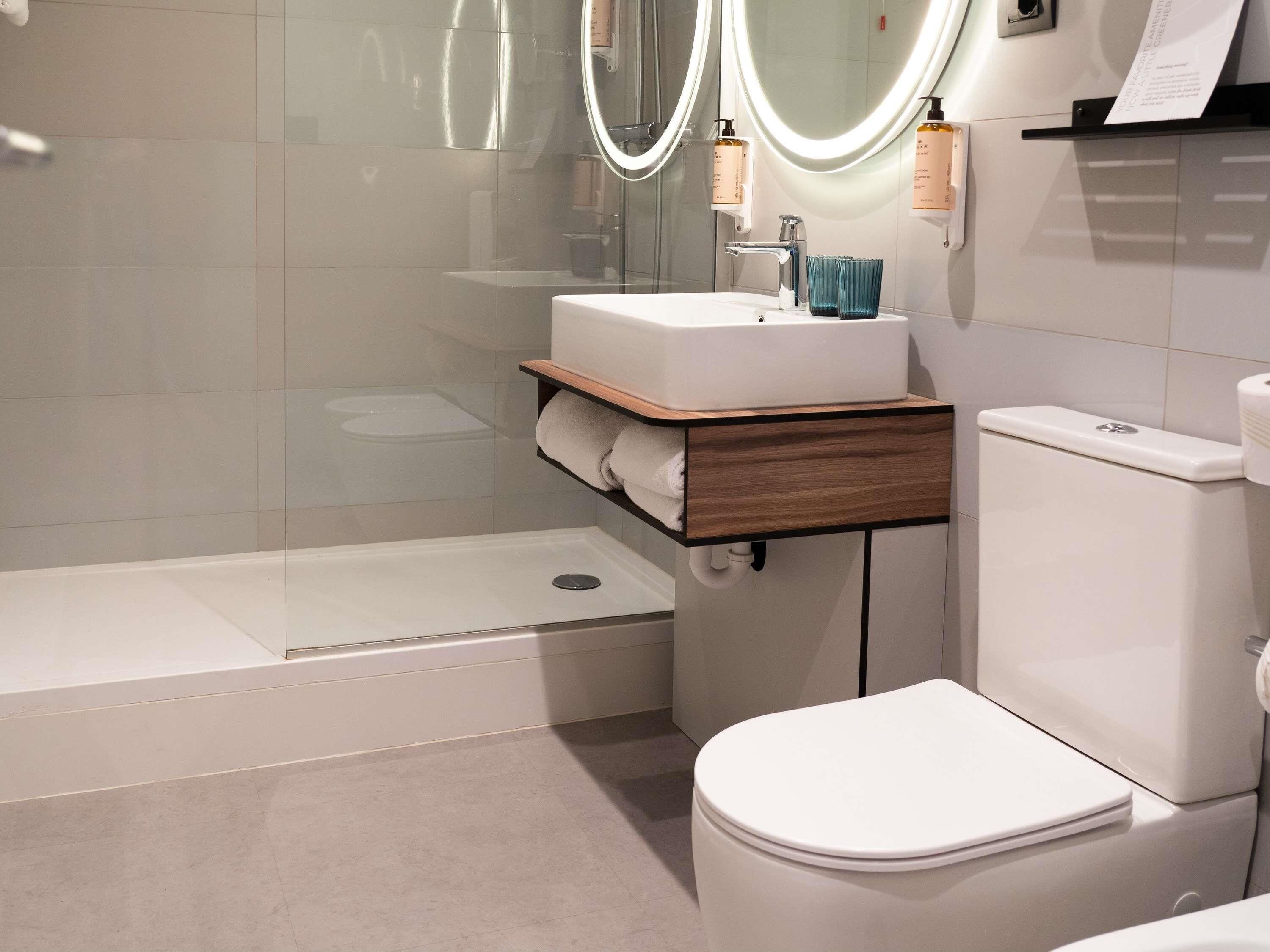 A modern bathroom with a shower, toilet, and vanity with a mirror.