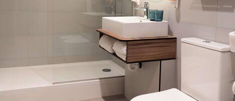 Une salle de bain moderne équipée d’une douche, de toilettes et d’un meuble-lavabo avec un miroir.
