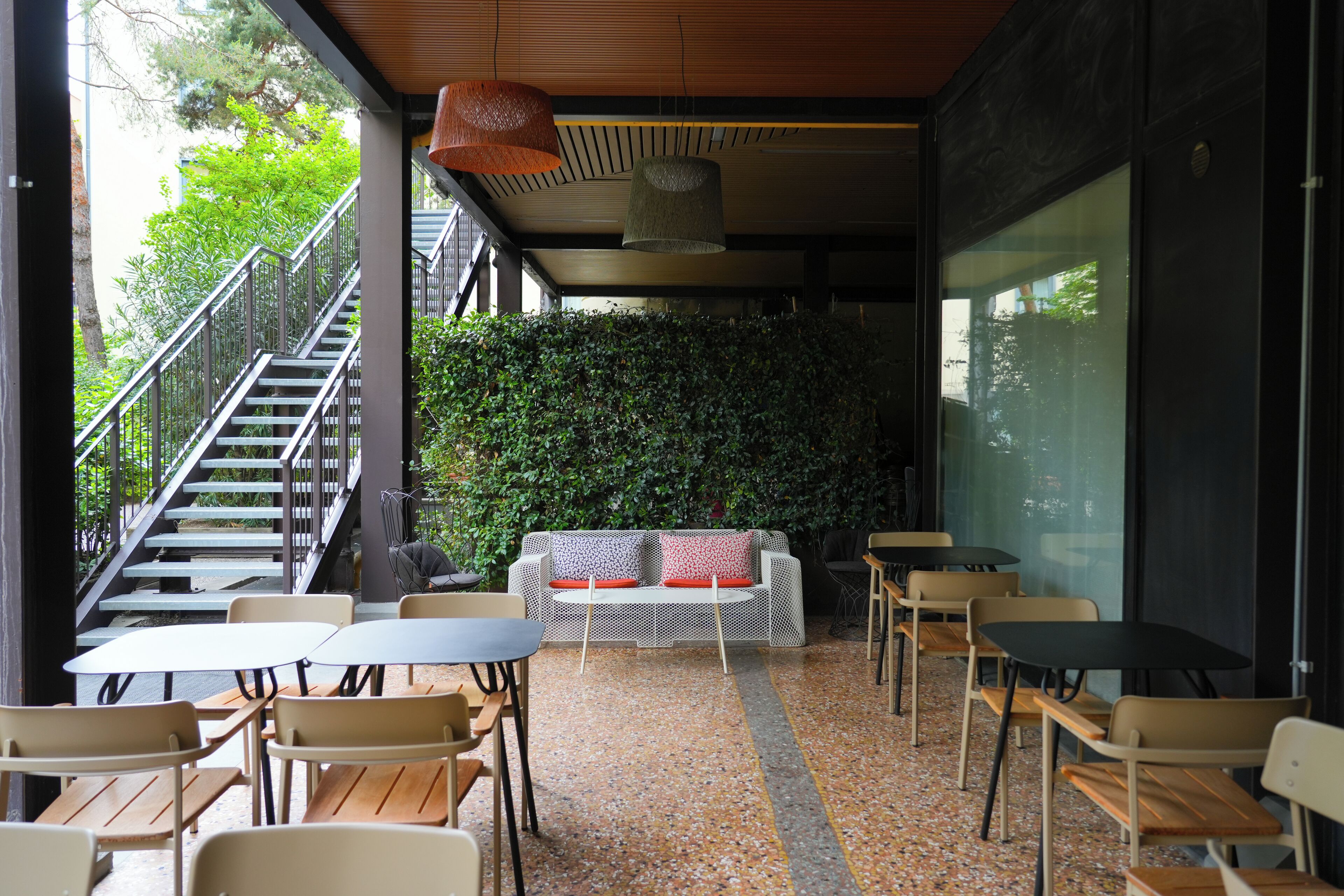 An indoor seating area with a staircase, a sofa with red cushions, and a green wall.