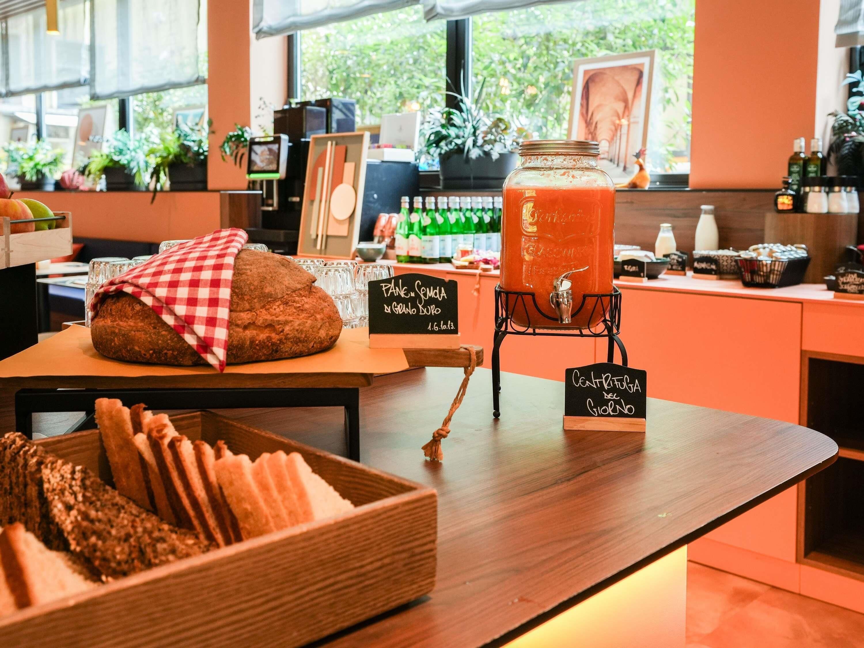 A bakery counter with bread, a jar of juice, and chalkboard signs.