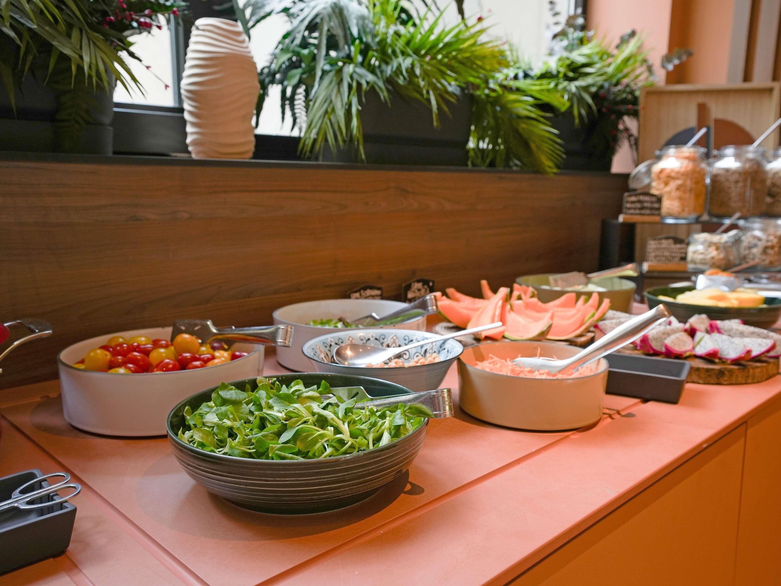Ein Buffet mit verschiedenen Speisen, darunter Salate, Früchte und Gemüse.