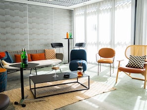 A modern living room with a sofa, chairs, a coffee table, and a patterned wall.
