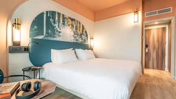 Una camera d'albergo con un letto grande, una scrivania con una sedia, un televisore a parete e una porta con pannello in legno.