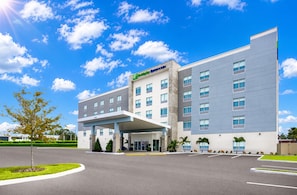 A modern hotel with a covered entrance, multiple floors, and a clear sky. - Holiday Inn Express & Suites Tampa Stadium – Airport Area by IHG (Tampa)