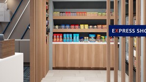 A hotel corridor with a wooden reception desk, a staircase, and a snack bar with various packaged goods. - Holiday Inn Express & Suites Tampa Stadium – Airport Area by IHG (Tampa)