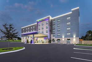 Un hotel Holiday Inn Express & Suites con un diseño moderno, que cuenta con una entrada cubierta y un estacionamiento.