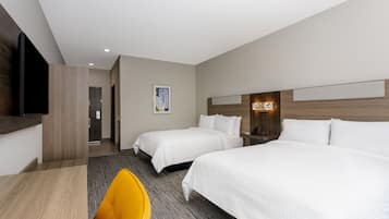 A hotel room with two beds, a desk, a chair, and a flat-screen TV.