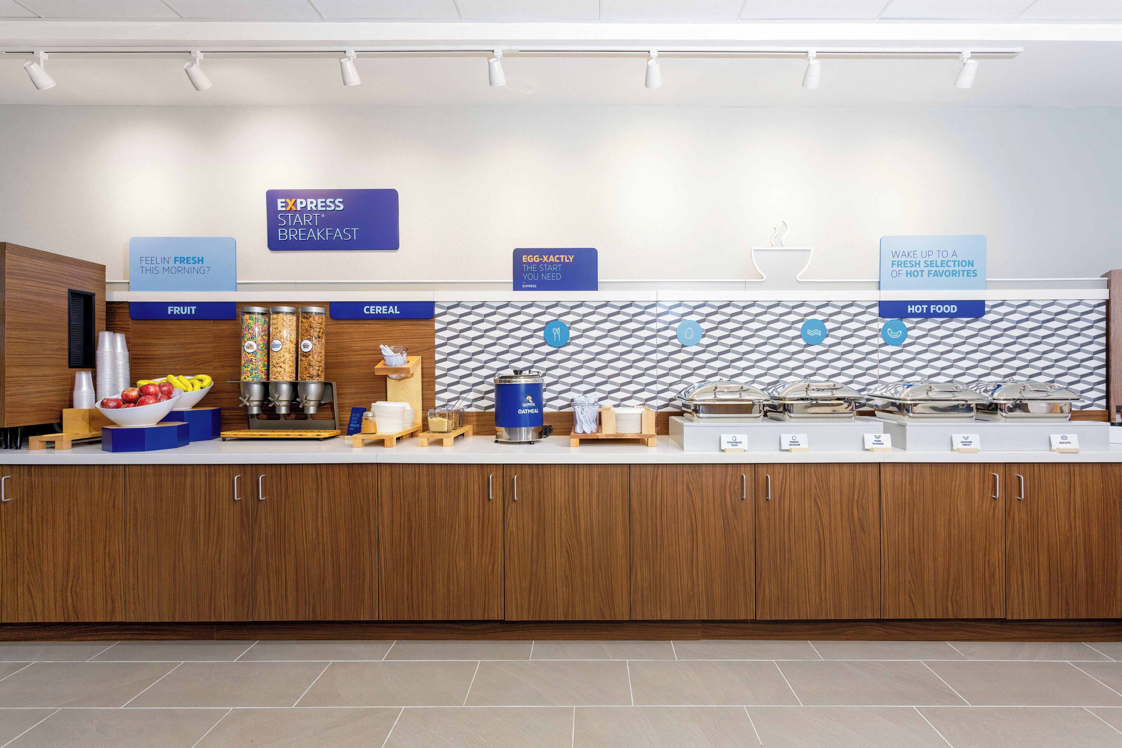Un espace buffet pour le petit-déjeuner, avec des sections clairement indiquées pour les fruits, les céréales et les plats chauds.