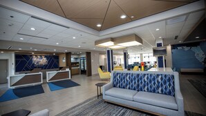 A modern lobby with a sofa, seating area, and a reception desk. - Holiday Inn Express & Suites Tampa Stadium – Airport Area by IHG (Tampa)
