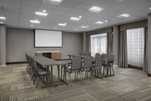 A conference room with a projector screen, a long table with chairs, and large windows with curtains. - Homewood Suites by Hilton Gaithersburg/ Washington, DC North (Gaithersburg)